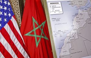 This picture taken on December 12, 2020 shows (L to R) US and Moroccan flags next to a US State Department-authorised map of Morocco recognising the internationally-disputed territory of the Western Sahara (bearing a signature by US Ambassador to Morocco David T. Fischer) as a part of the North African kingdom, in Morocco's capital Rabat. (Photo by AFP)